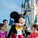Mickey greets a little boy in front of his family and Cinderella Castle